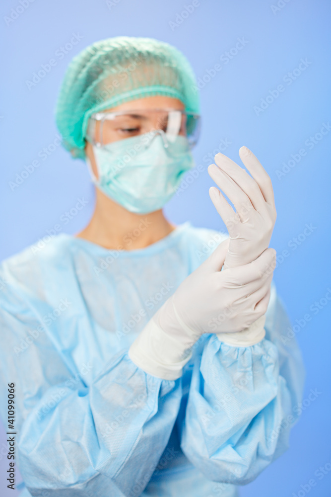 Young beautiful surgeon doctor (woman) before operation on blue