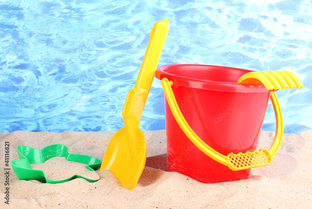 Children's beach toys on sand on water background Children's beach toys on sand on water background