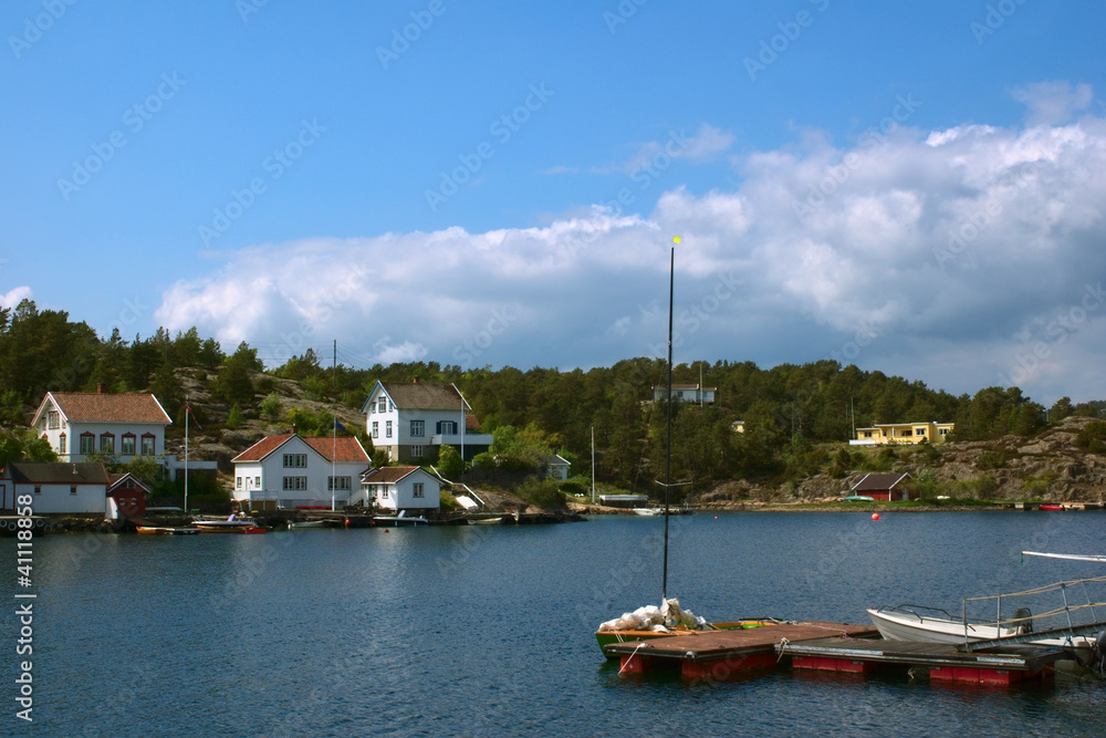 Anlegestelle mit Segelboot und weiße Häuser in Lyngor, Norwegen