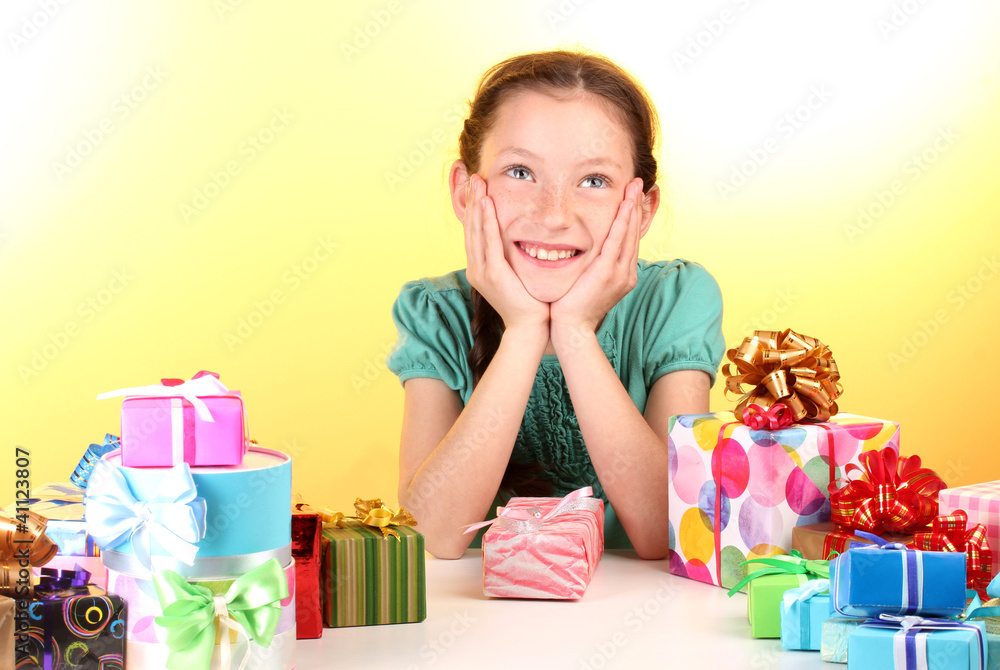 Little girl with gifts on yellow background Little girl with gifts on yellow background