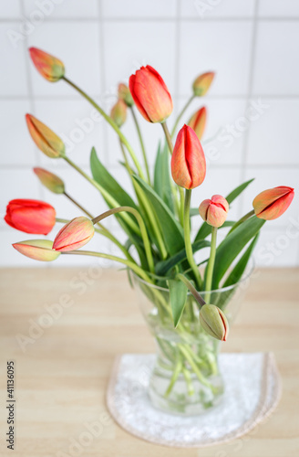 Vase mit einem Blumenstrauß roter Tulpen.