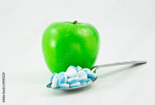 green apple and spoon full of pills