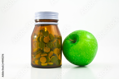 Medicine glass bottle with pills and apple