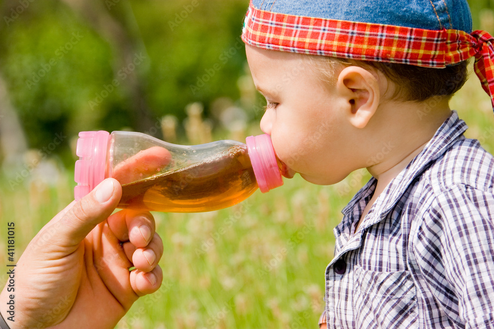 Obraz premium Beautiful boy drinking from plastic bottle