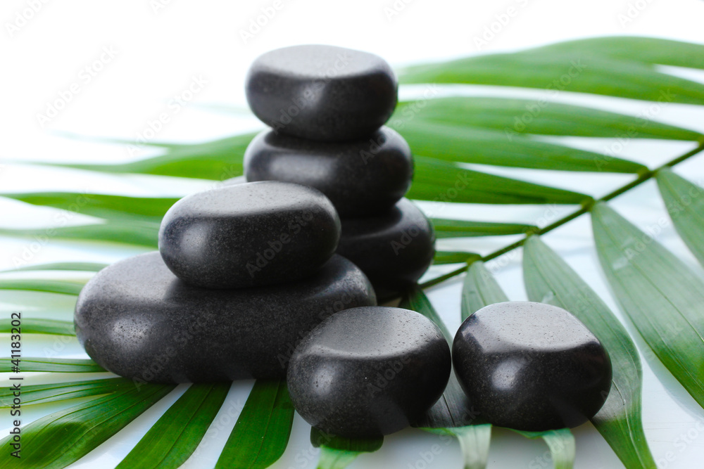 Spa stones on green palm leaf isolated on white Spa stones on green palm leaf isolated on white