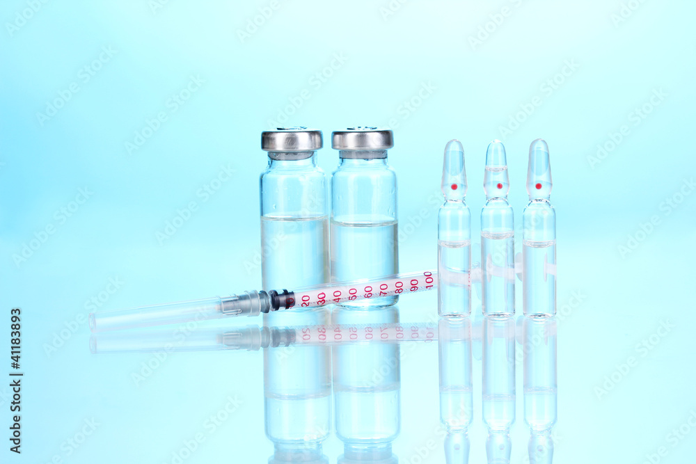 Syringe and medical ampoules on blue background Syringe and medical ampoules on blue background