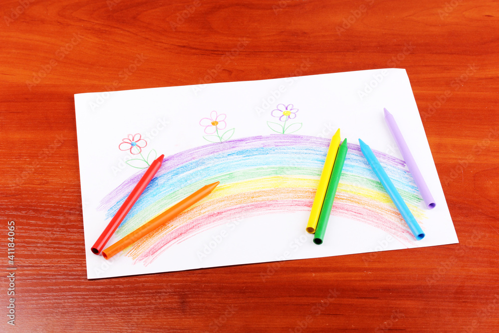Children's drawing of rainbow and pencils on wooden background Children's drawing of rainbow and pencils on wooden background