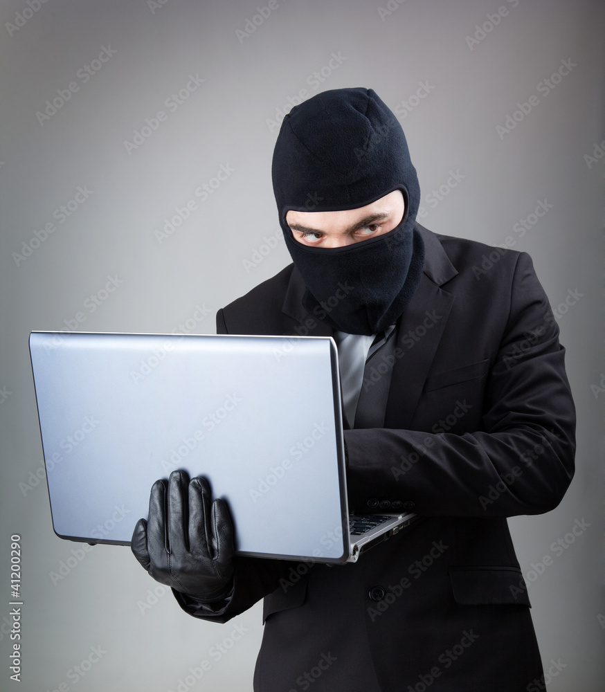 Computer Hacker in suit and tie stealing data from laptop comput Computer Hacker in suit and tie stealing data from laptop comput