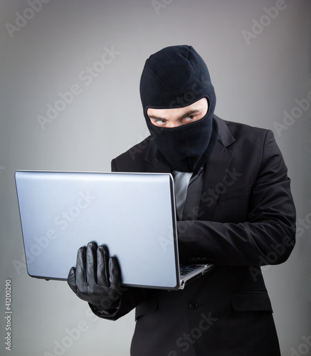 Computer Hacker in suit and tie stealing data from laptop comput