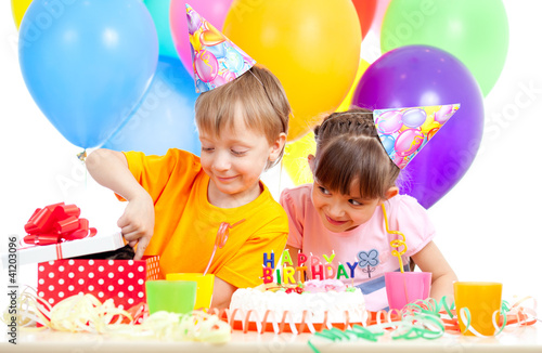 adorable children celebrating birthday party and opening gift bo