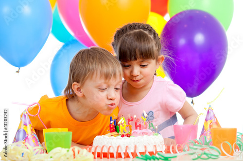 kids celebrating birthday party and blowing candles on cake
