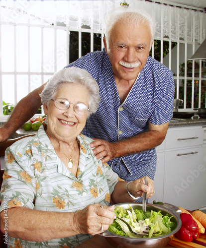 Señores abuelos cocinando en una cocina.Comiendo ensalada.