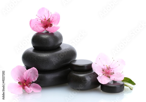 Spa stones and pink sakura flowers isolated on white.