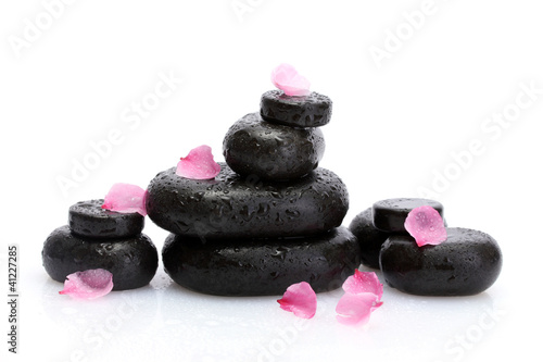 Spa stones with drops and pink petals isolated on white.