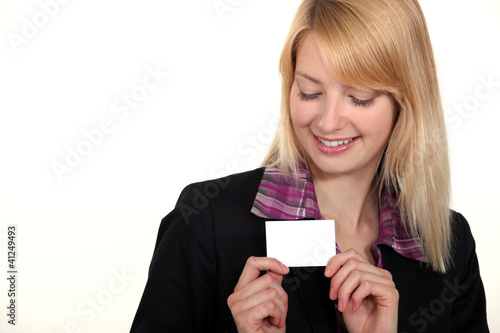 blonde businesswoman with downcast eyes showing business card