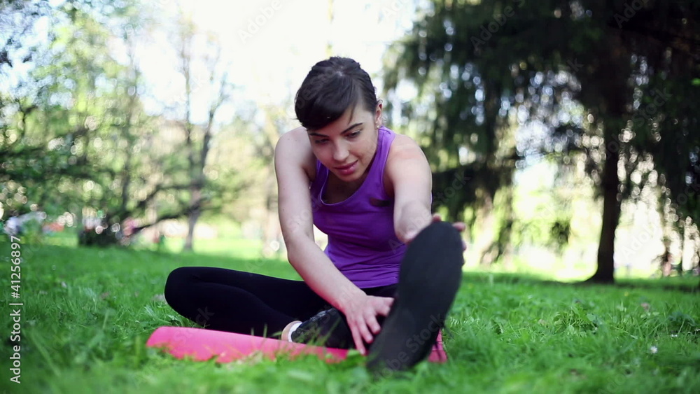 Young woman stretching, exercising in the park, dolly shot Young woman stretching, exercising in the park, dolly shot