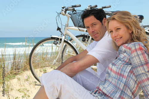 Couple with bikes sitting on the sand dunes #41258604