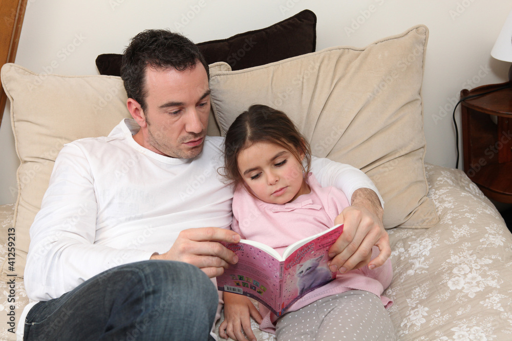 Man reading story to little girl in bed Man reading story to little girl in bed