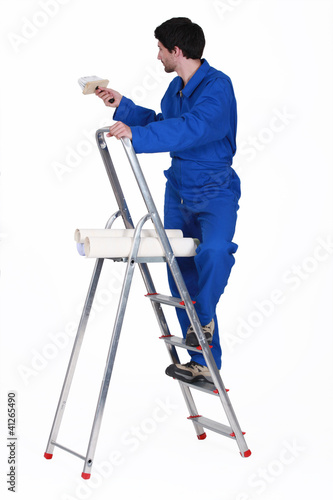 painter in jumpsuit on ladder isolated on white
