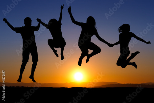 silhouette of kids jumping on beach in sunset © Alex Koch