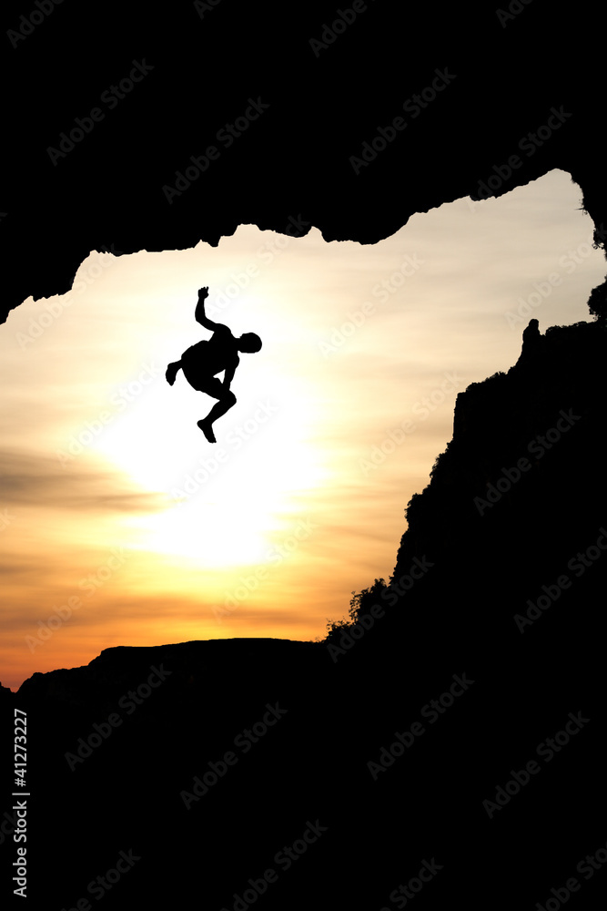 silhouette of man jumping of rock