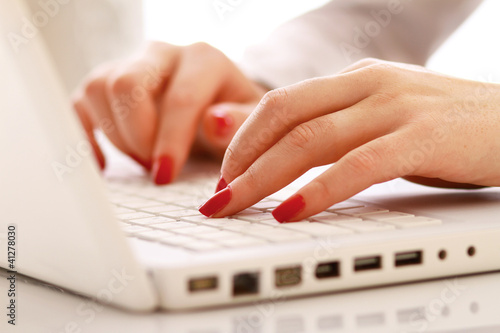 Close-up of woman typing documents on keyboard of laptop.