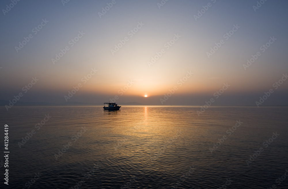 Small fishing boat at sunrise on a calm sea