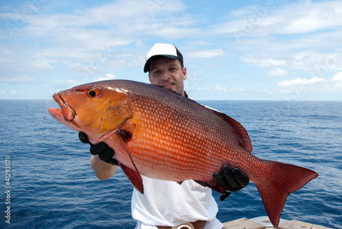 Happy  fisherman holding a beautiful red snapper photo