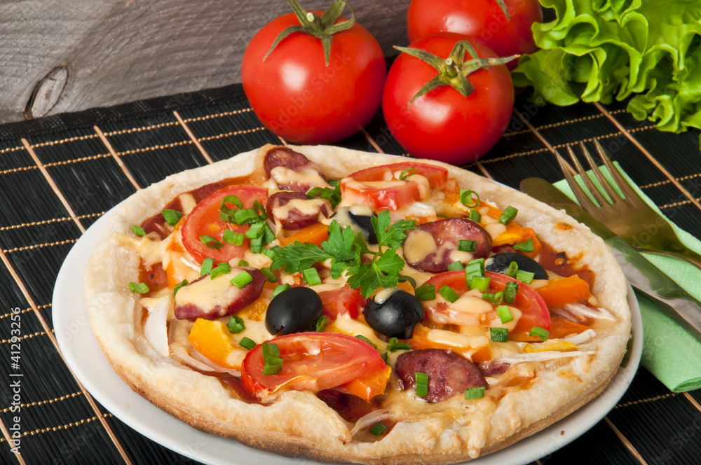 Closeup of pizza with tomatoes, cheese, black olives and peppers