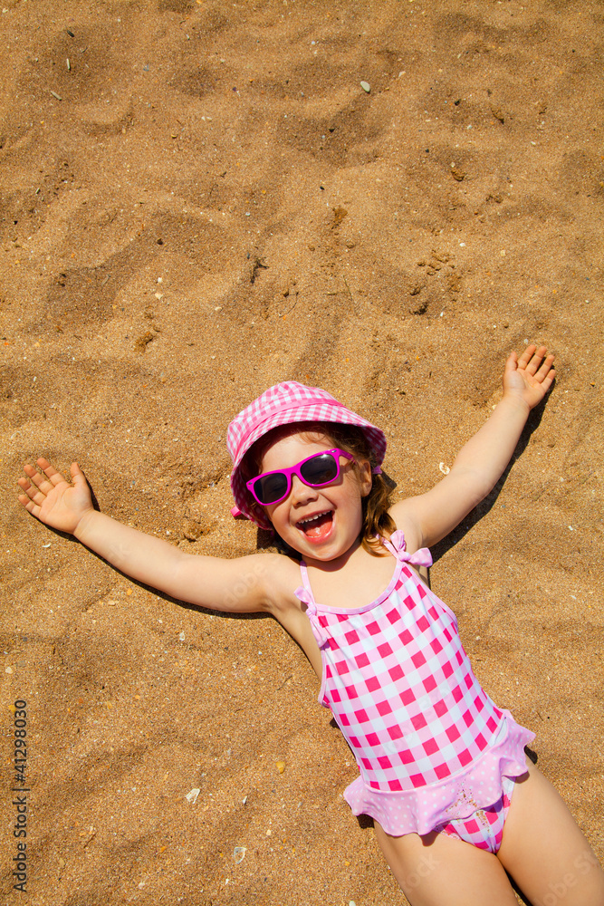 little girl lying on sandy beach Stock Photo | Adobe Stock