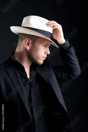 Young man portrait with white hat on black background.