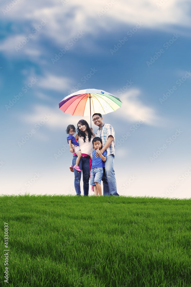 Happy family with colorful umbrella in meadow Happy family with colorful umbrella in meadow