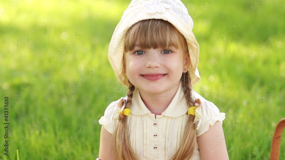 Girl eating lollipop and sitting on the grass