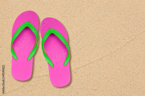 pink and green flip flops on the beach with space