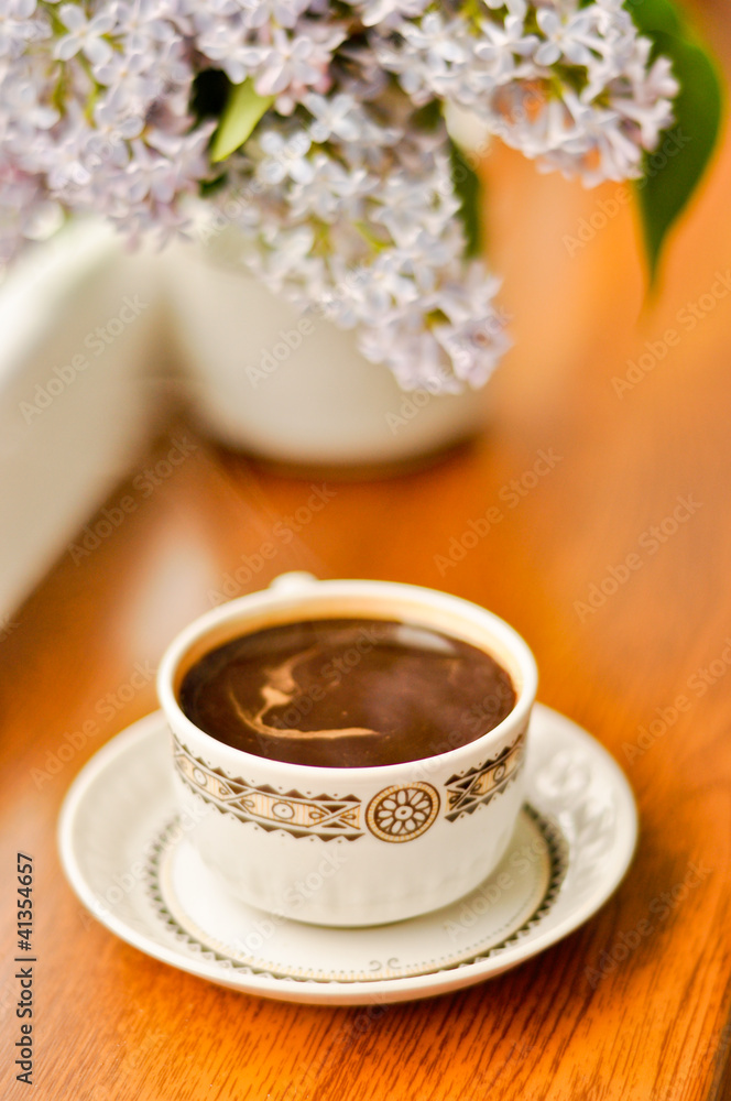Ceramic cup with coffee and bouquet of lilac Ceramic cup with coffee and bouquet of lilac