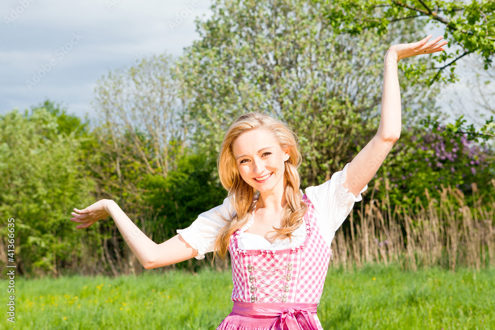 Junge Frau mit einem rosa farbenen Dirndl in einer grünen Wiese Junge Frau mit einem rosa farbenen Dirndl in einer grünen Wiese