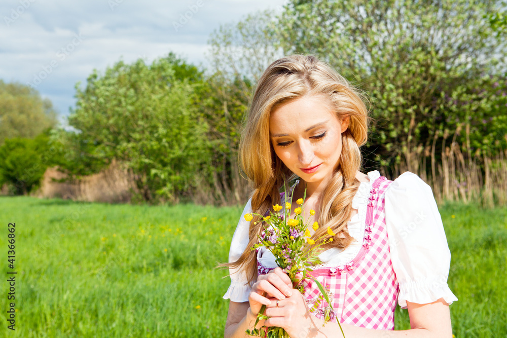 Junge Frau mit einem rosa farbenen Dirndl in einer grünen Wiese Junge Frau mit einem rosa farbenen Dirndl in einer grünen Wiese