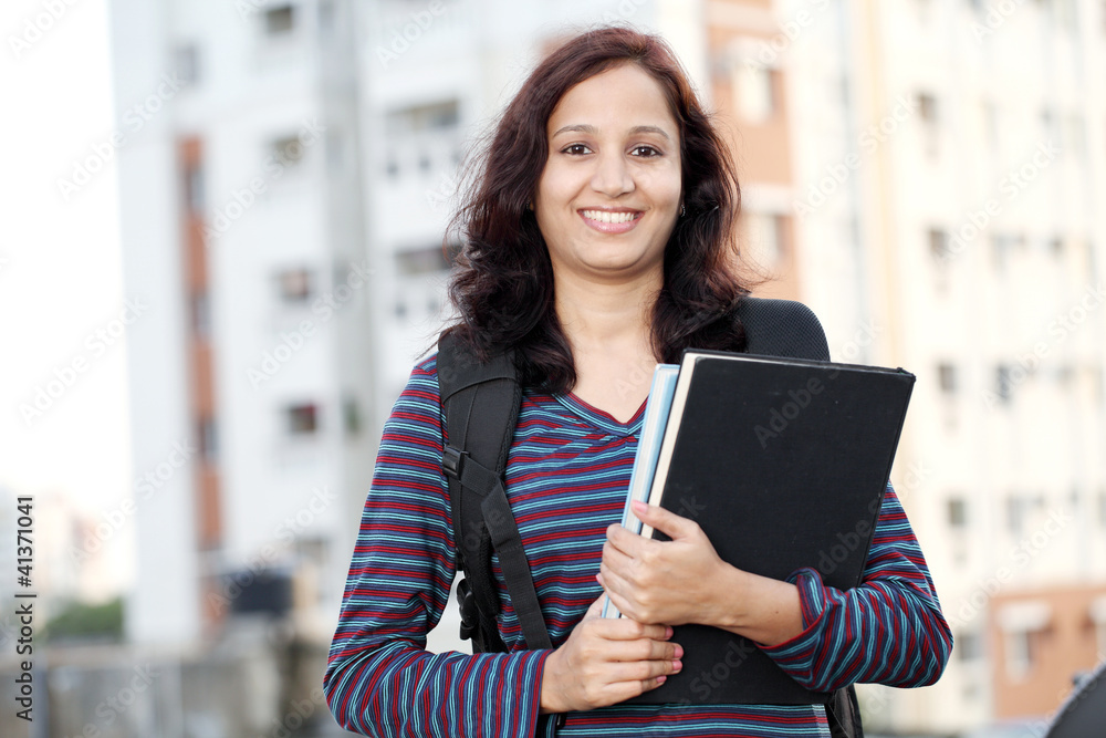 Cheerful female student holding text books Cheerful female student holding text books