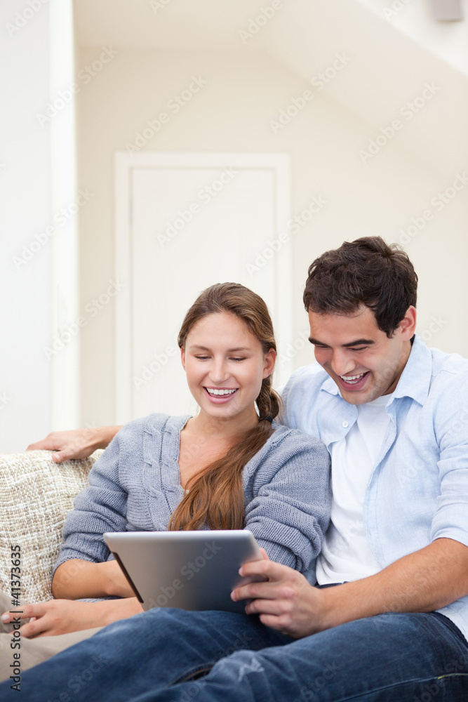 Couple laughing while holding a laptop Couple laughing while holding a laptop