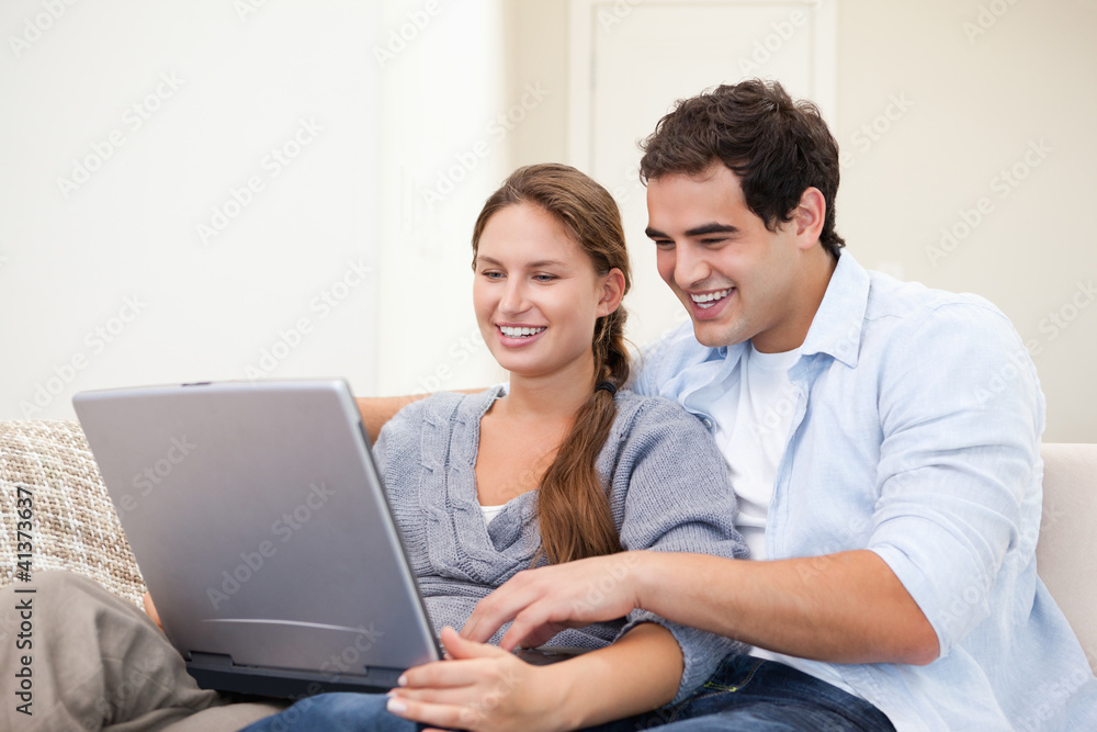 Couple sitting on a sofa while holding a laptop Couple sitting on a sofa while holding a laptop