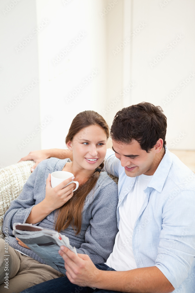 Couple sitting on a sofa while reading a newspaper Couple sitting on a sofa while reading a newspaper