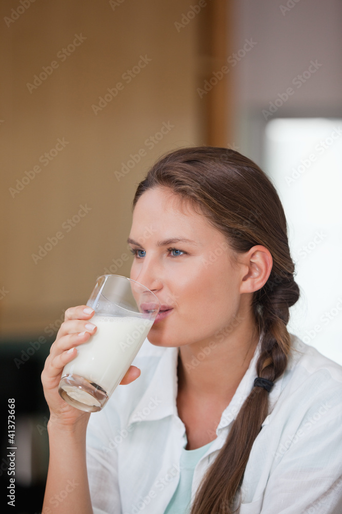 Woman drinking a glass of milk while looking away Woman drinking a glass of milk while looking away