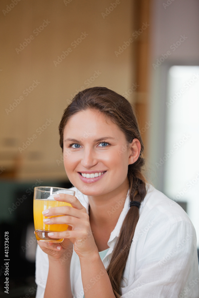 Woman drinking orange juice while smiling Woman drinking orange juice while smiling