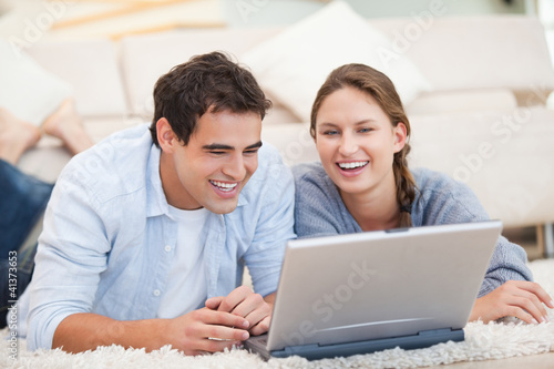 Young Couple lying while using a computer © WavebreakmediaMicro