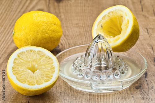 Canvas Print cut lemons and juicer on wooden board