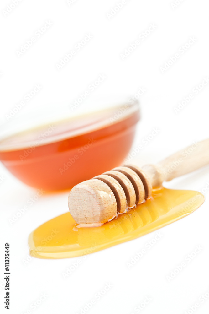Honey dipper on the floor spilling honey in front of a honey bow Honey dipper on the floor spilling honey in front of a honey bow