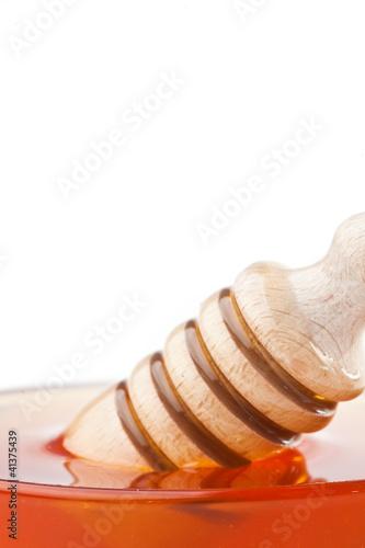 Close up of a honey dipper in a honey bowl