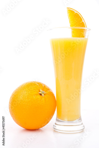 Orange placed next to a glass of orange juice