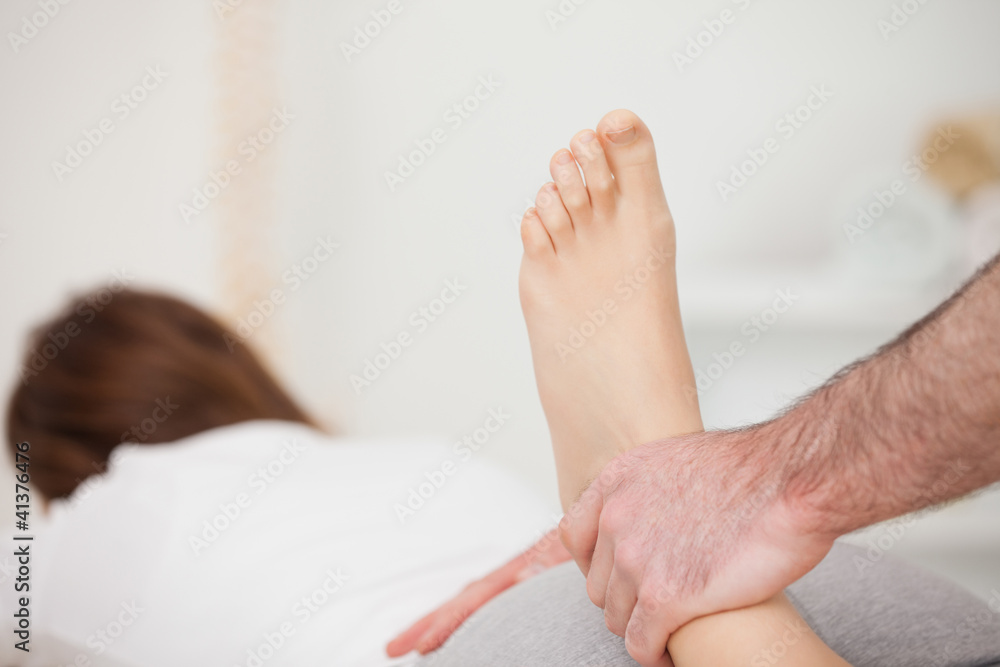Woman lying forward while a physio manipulates her foot Woman lying forward while a physio manipulates her foot