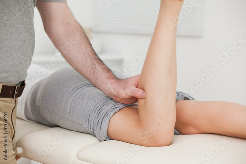 Woman lying forward while a physiotherapist bends her leg